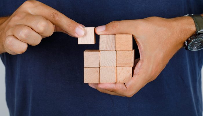Young man in dark blue t-shirt holding one of wooden blocks , front view. Young man in dark blue t-shirt holding one of wooden blocks , front view.